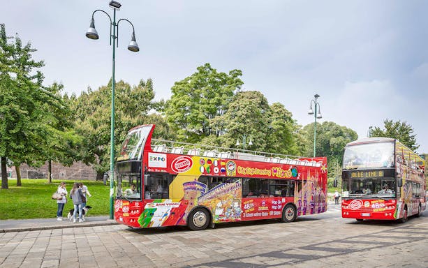City Sightseeing Milan hop-on hop-off buses at a passenger stop.