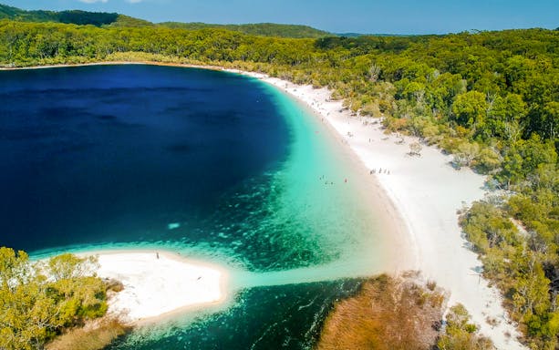 Aerial view of Lake McKenzie on Fraser Island, K'gari, with clear blue water and white sandy shores.