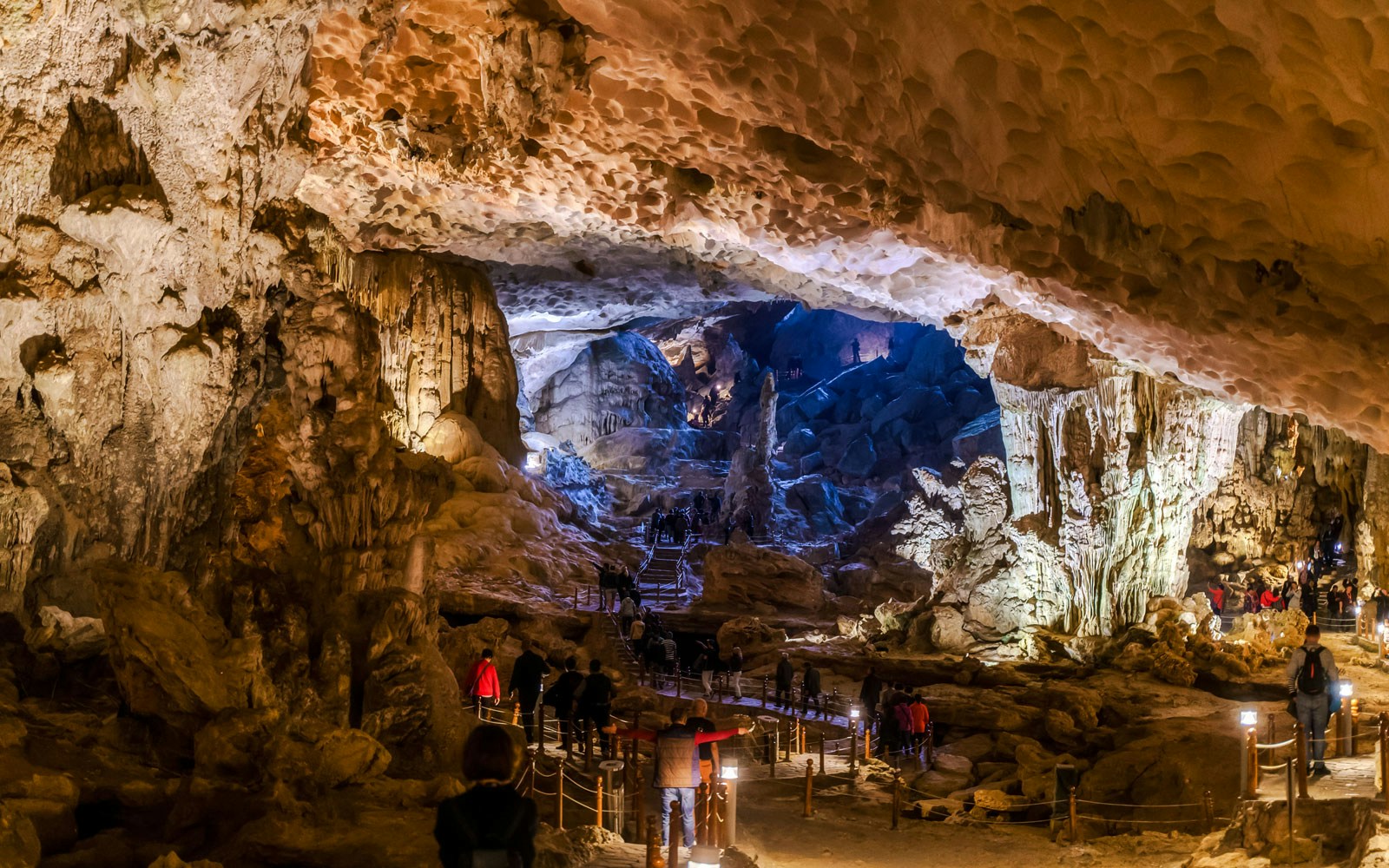 Visitors exploring the illuminated stalactites and rock formations inside Thien Cung Cave, Vietnam.