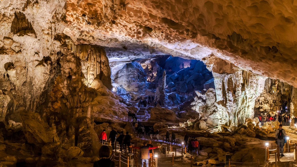 Visitors exploring the illuminated stalactites and rock formations inside Thien Cung Cave, Vietnam.