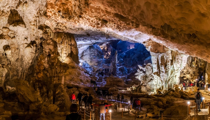 Visitors exploring the illuminated stalactites and rock formations inside Thien Cung Cave, Vietnam.