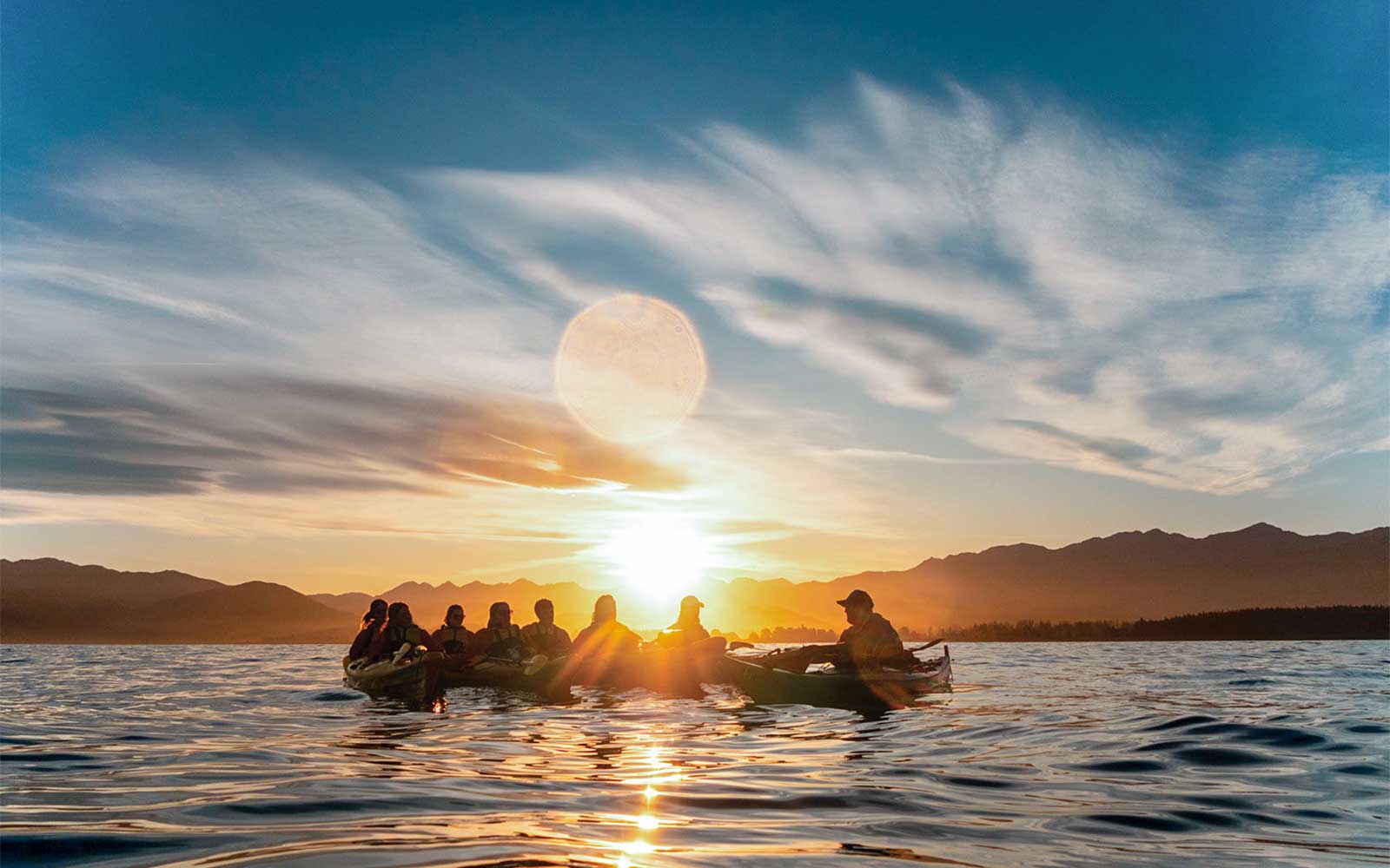 Kayakers paddling at sunset during a guided wildlife tour on a serene lake.