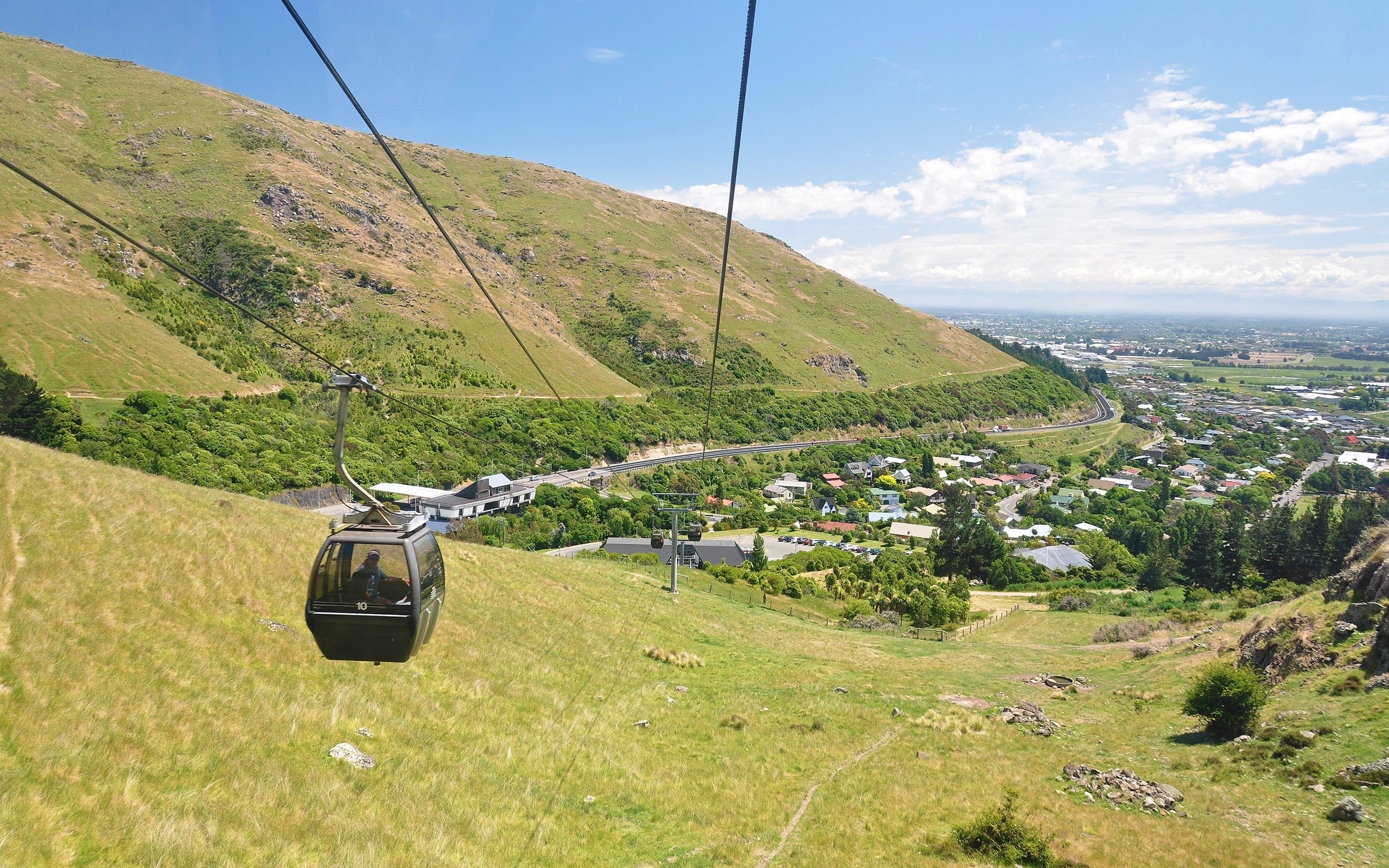 Gondola ascending over hills and cityscape in Christchurch, New Zealand.