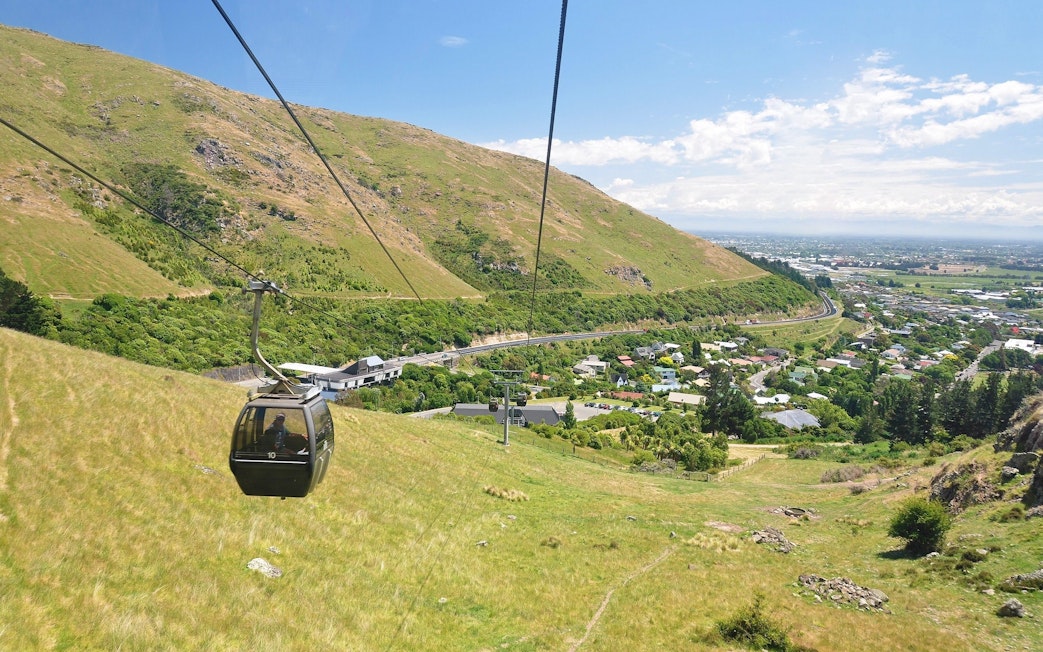 Gondola ascending over hills and cityscape in Christchurch, New Zealand.