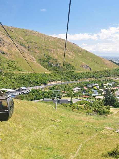Gondola ascending over hills and cityscape in Christchurch, New Zealand.