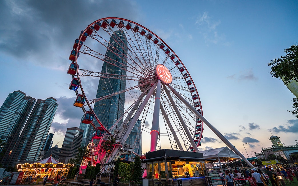 Hong Kong Observation Wheel at sunset with city skyline in the background.