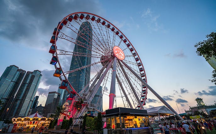 Hong Kong Observation Wheel at sunset with city skyline in the background.