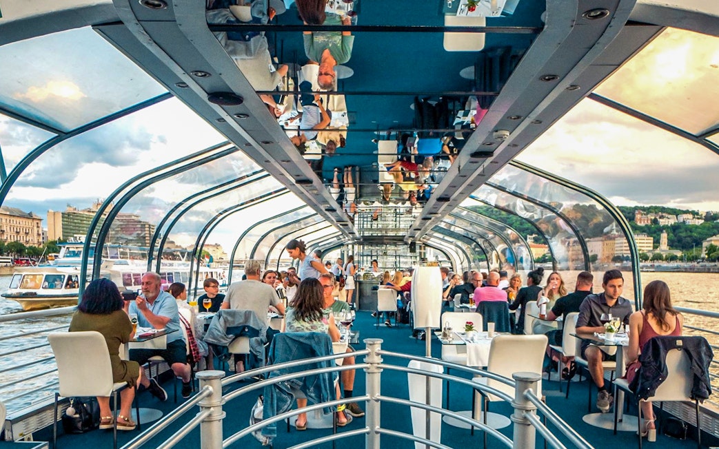 Budapest dinner cruise with guests dining under a glass roof on the Danube River.