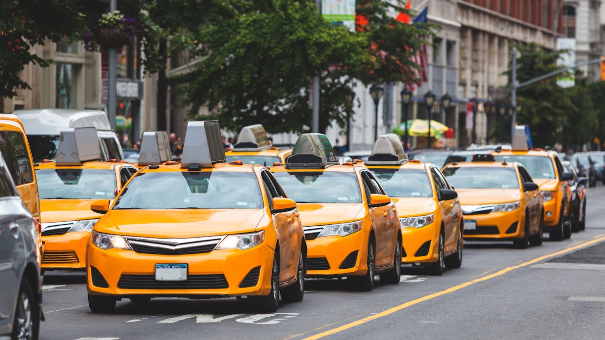 Yellow taxis lined up on a street in New York City.