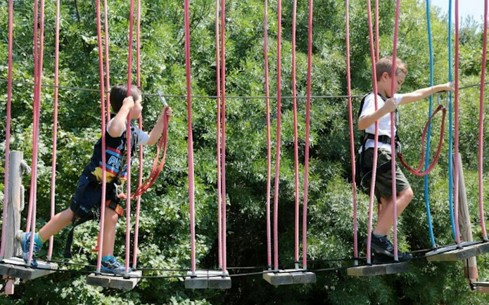 Children navigating a rope bridge at Theme Park Oltremare.