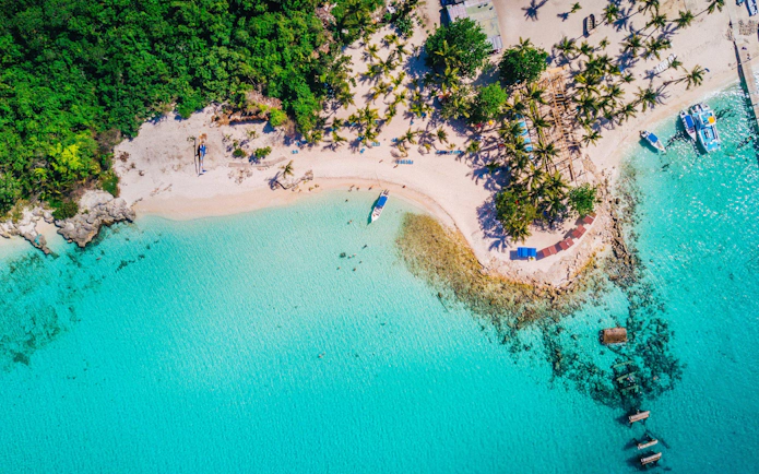 Aerial view of Saona Island, Punta Cana, showing beach, boats, and tropical vegetation.
