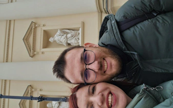 Couple smiling in front of a historic building in Warsaw during a self-guided city exploration game.