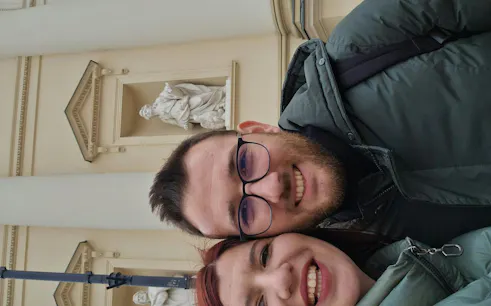Couple smiling in front of a historic building in Warsaw during a self-guided city exploration game.