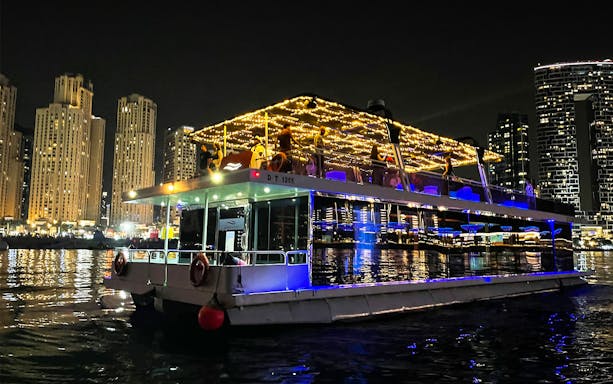 Houseboat with lights on Dubai Marina at night during Ain Dubai tour.