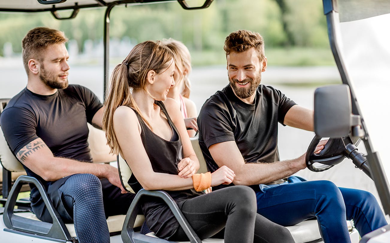 Friends enjoying a ride in a golf cart.