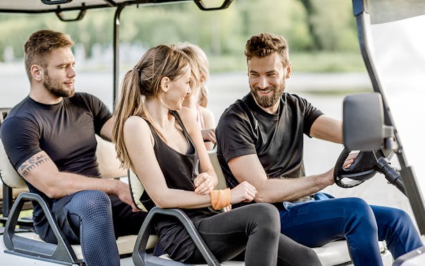 Friends enjoying a ride in a golf cart.