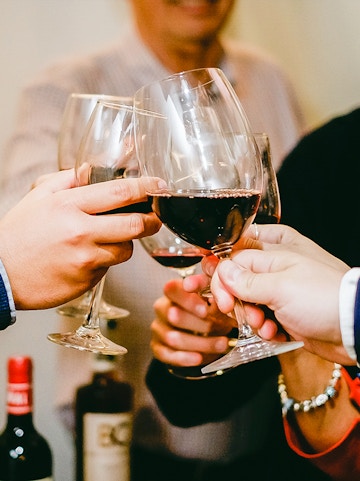 People toasting with red wine glasses during a Barcelona culinary tour.