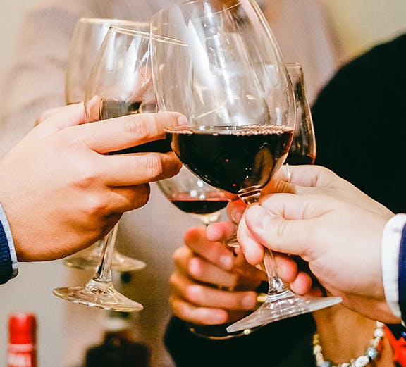 People toasting with red wine glasses during a Barcelona culinary tour.