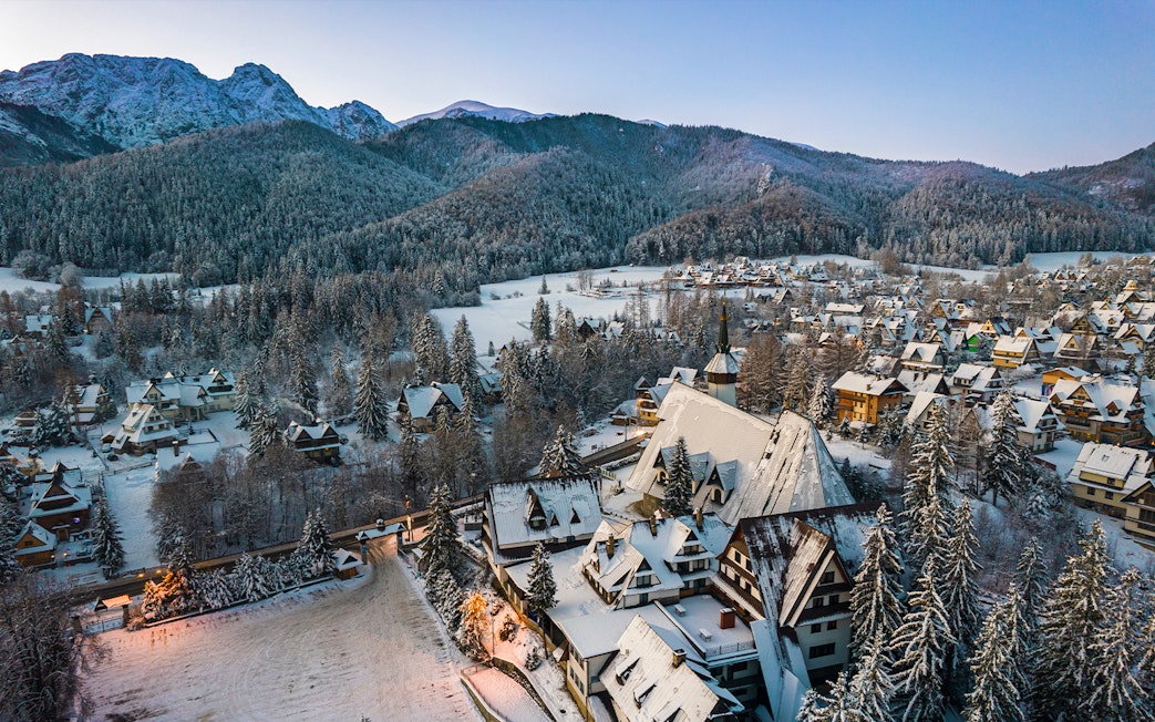 Aerial view of snow-covered Zakopane village with Tatra Mountains in the background, Poland.
