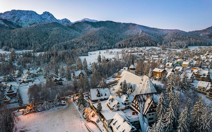 Aerial view of snow-covered Zakopane village with Tatra Mountains in the background, Poland.