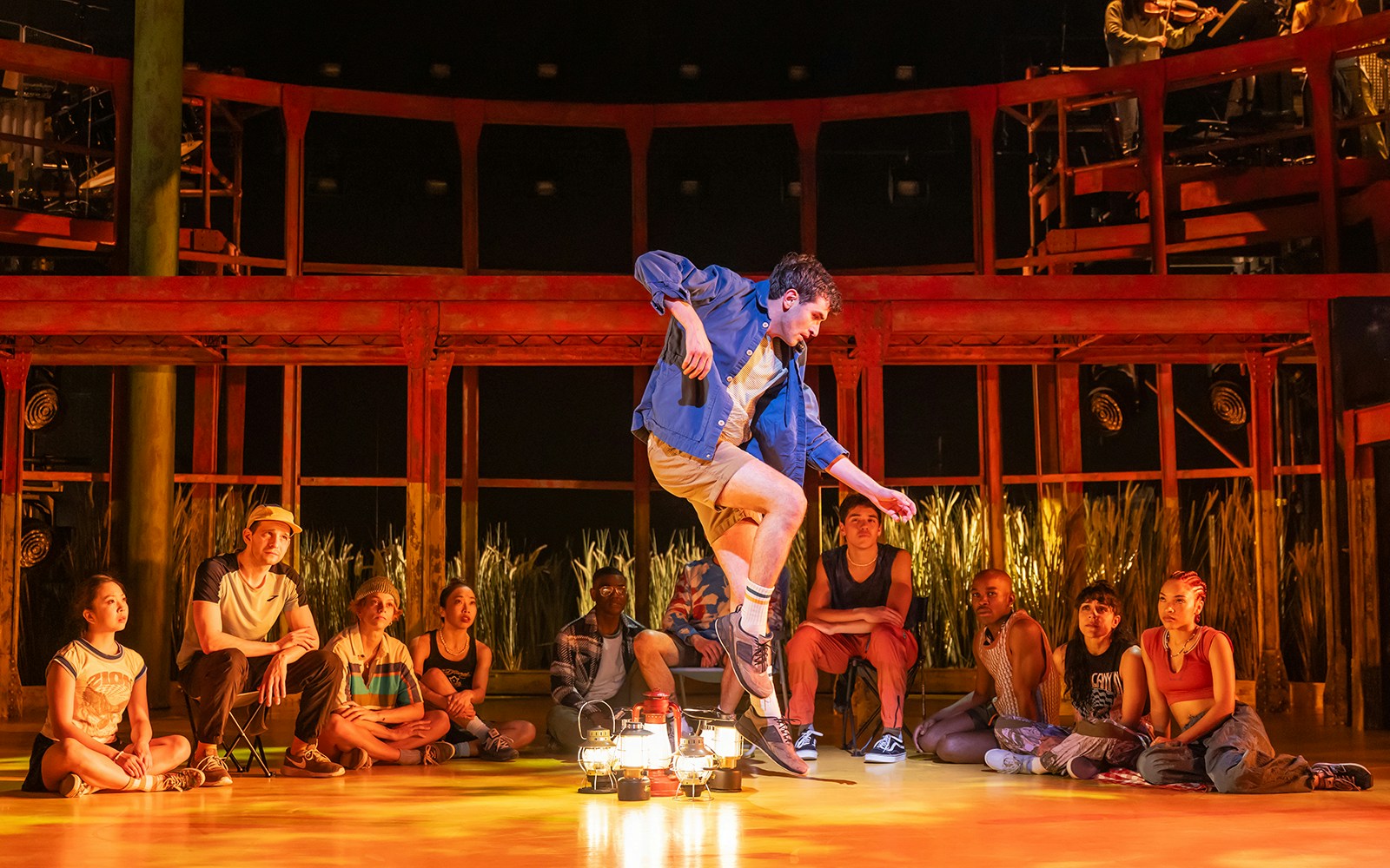 Performer dancing on stage surrounded by seated audience in Illinois theater.