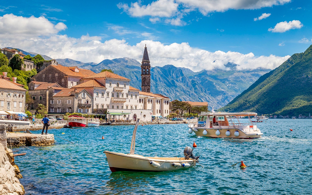 Kotor Bay with boats and historic buildings against mountain backdrop.