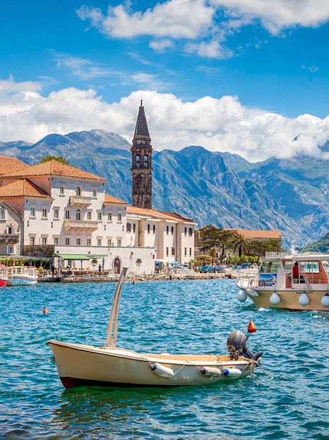 Kotor Bay with boats and historic buildings against mountain backdrop.