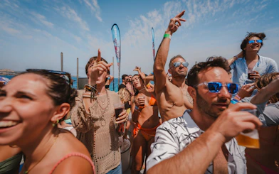 Tourists enjoying a lively Cruise Crush Boat Party under a clear blue sky.