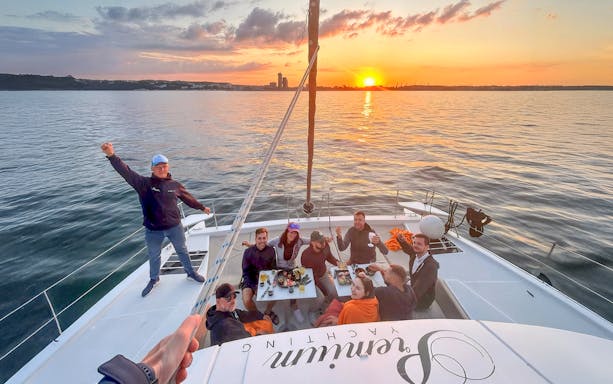 Guests dining on a catamaran during a breakfast cruise at sunrise.