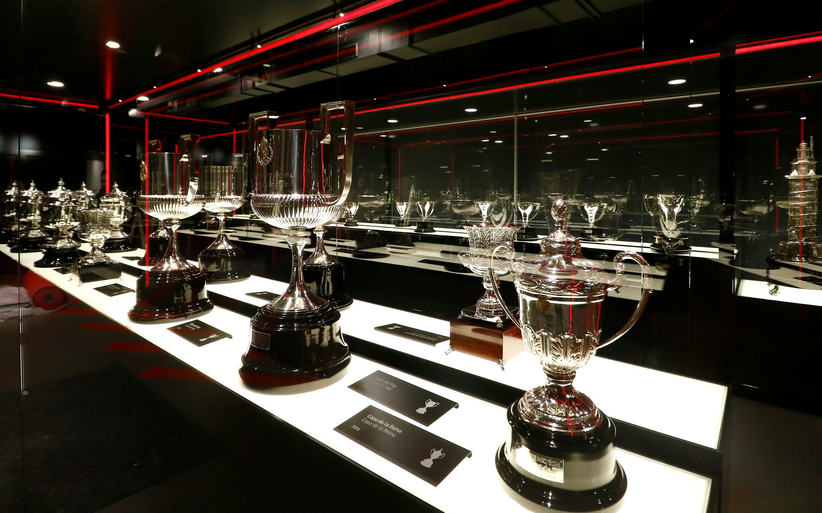Atlético Madrid stadium museum trophy display with various silver cups.