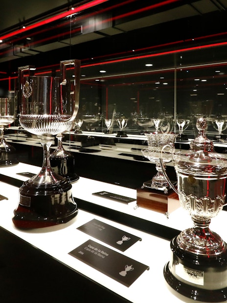 Atlético Madrid stadium museum trophy display with various silver cups.