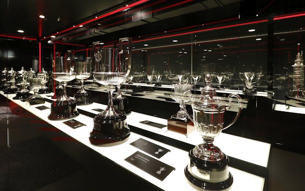 Atlético Madrid stadium museum trophy display with various silver cups.