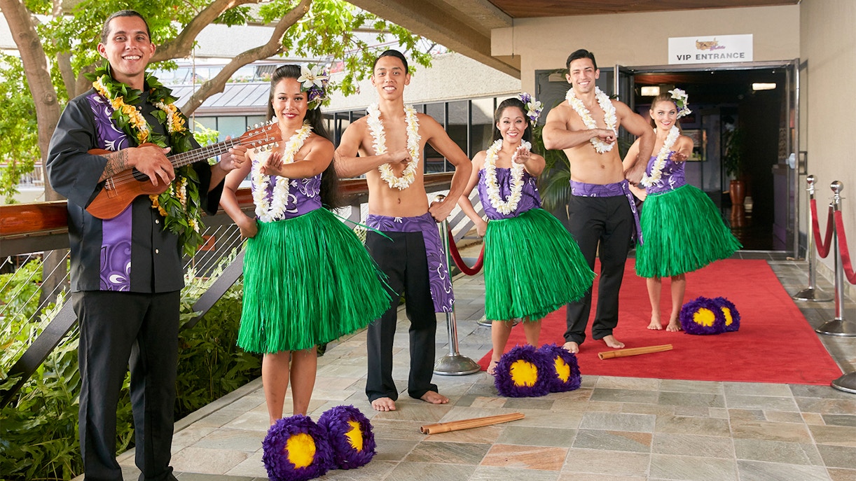 Performers in traditional attire welcome guests at Rock-A-Hula Show entrance.