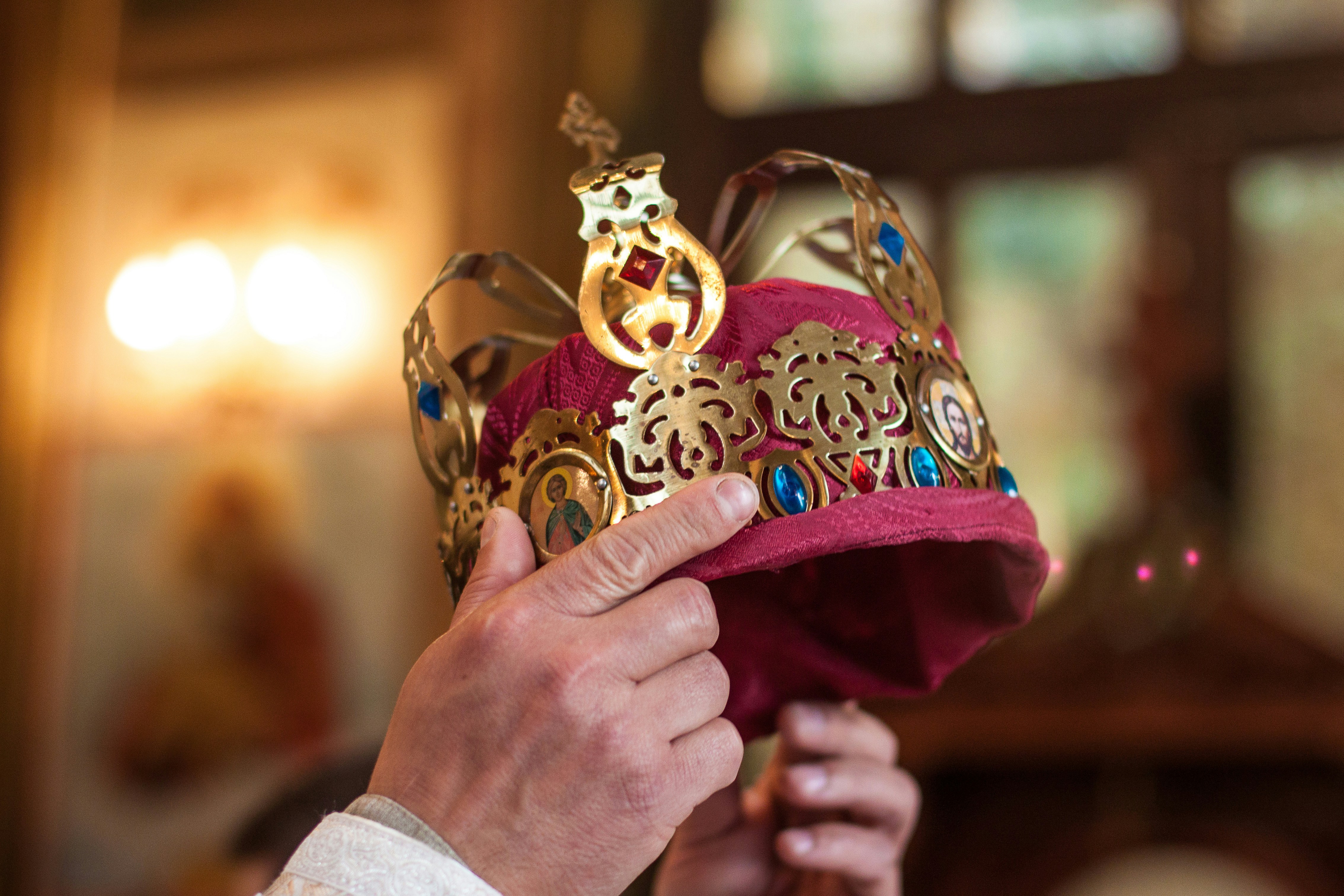 Ornate crown being held during a coronation ceremony.