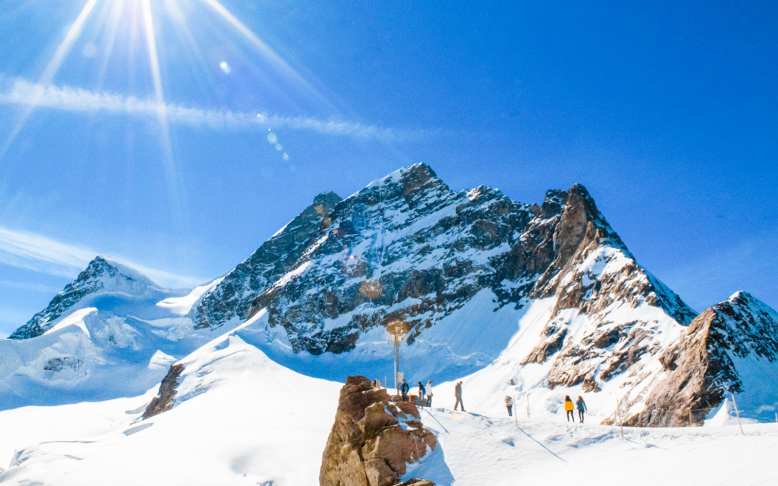 Hikers on Northeast Ridge trail with snow-capped Jungfrau mountain in background, Switzerland.