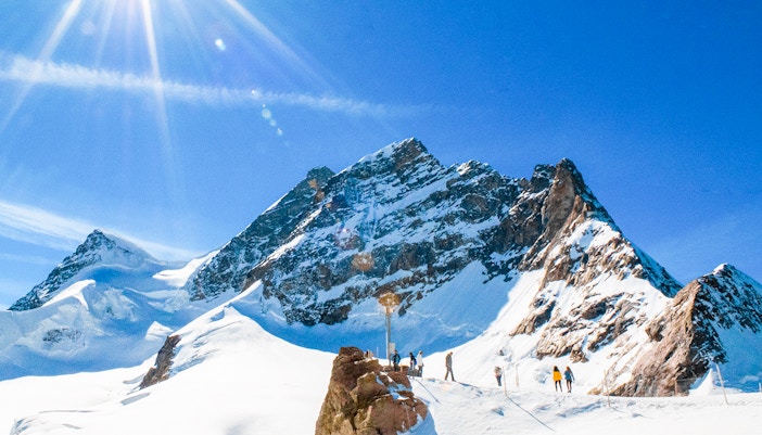 Hikers on Northeast Ridge trail with snow-capped Jungfrau mountain in background, Switzerland.