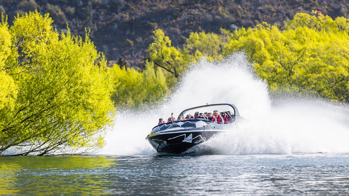 Jet boat speeding on Kawarau River with passengers enjoying the ride.