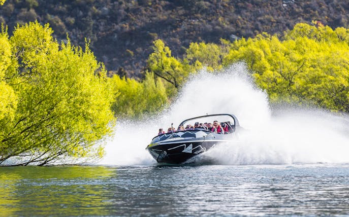 Jet boat speeding on Kawarau River with passengers enjoying the ride.
