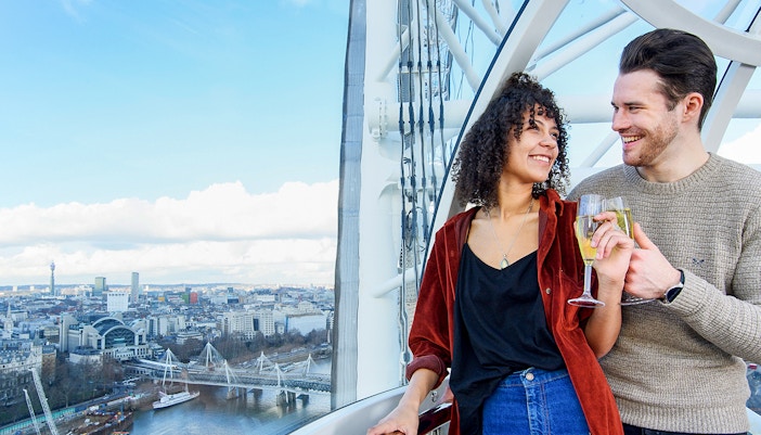 Couple enjoying champagne on the London Eye with cityscape view.