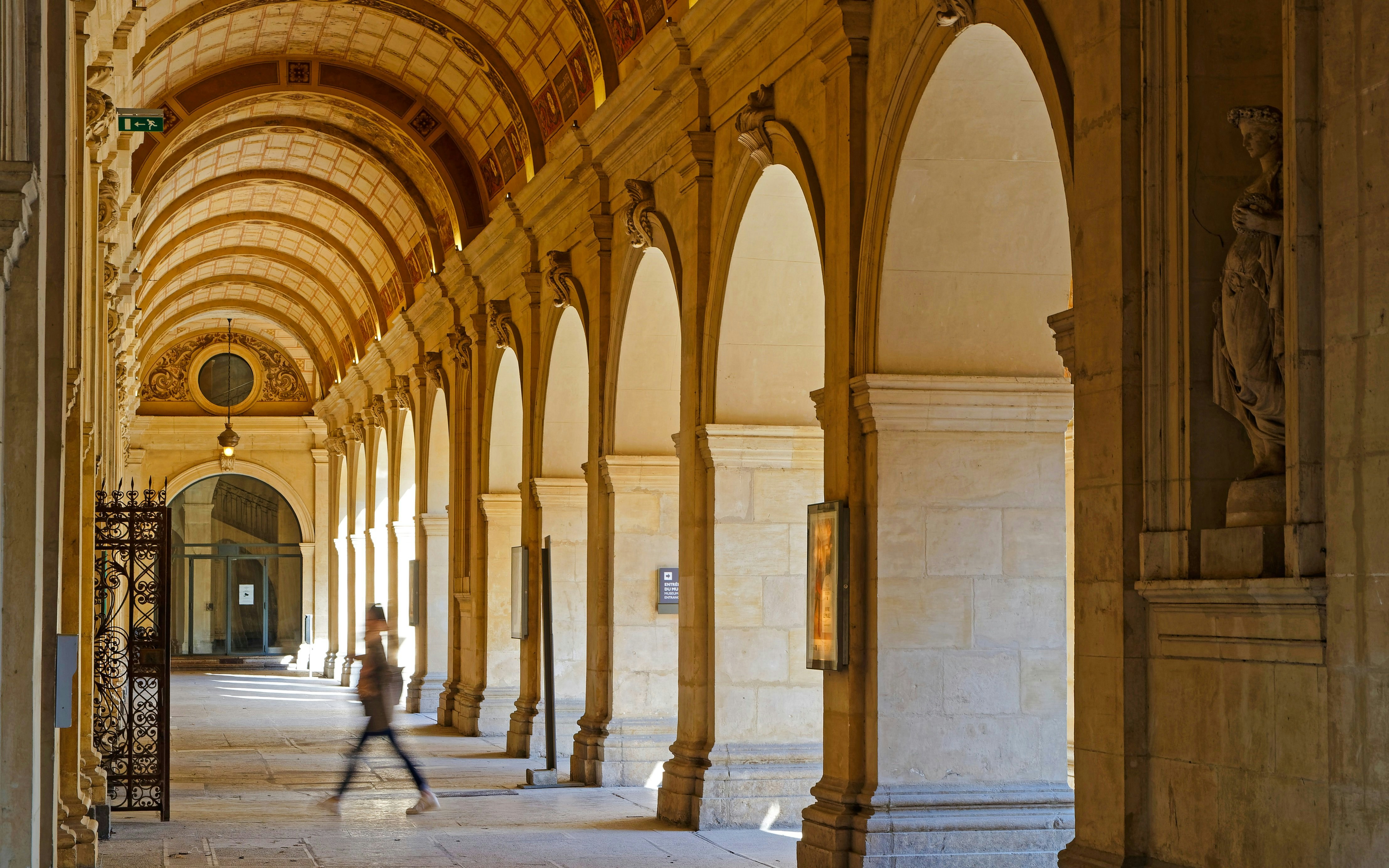 Arched hallway inside the Museum of Fine Arts Lyon with a person walking.