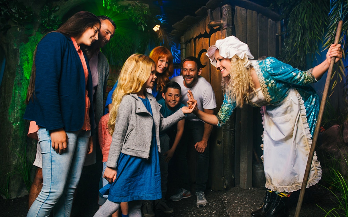 Group interacting with a costumed guide in a themed attraction setting.