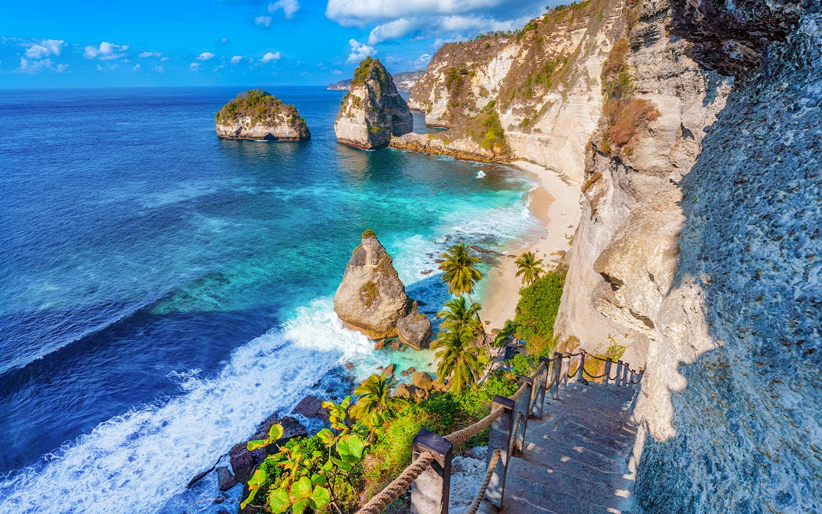 Tourists descending the stairs to the stunning Diamond Beach in Nusa Penida, offering exclusive access to a unique viewpoint of the sparkling shoreline.