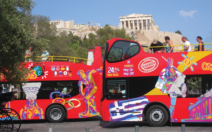 HOHO tour bus in Athens with Acropolis in the background.
