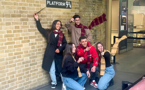 Visitors posing with wands at Platform 9 3/4, King's Cross Station, London.