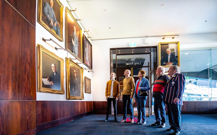 Visitors viewing sports portraits in Melbourne's Long Room during a guided walk.