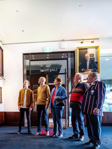 Visitors viewing sports portraits in Melbourne's Long Room during a guided walk.
