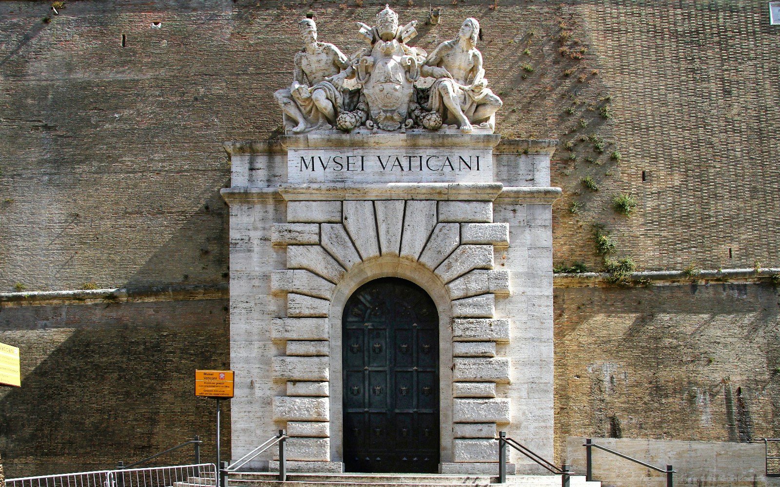 Entrance to the Vatican Museums with sculptures above the door in Rome.