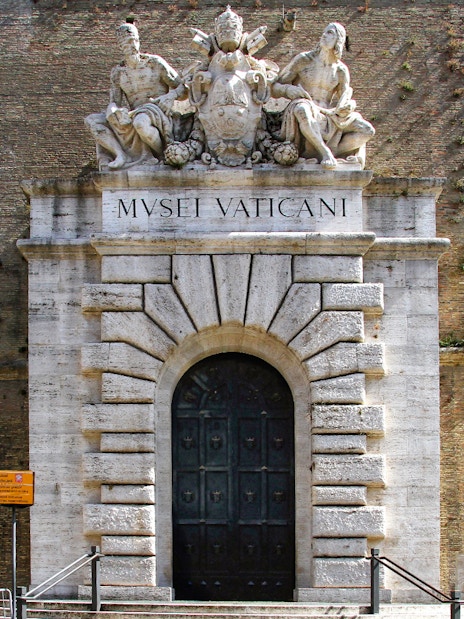 Entrance to the Vatican Museums with sculptures above the door in Rome.