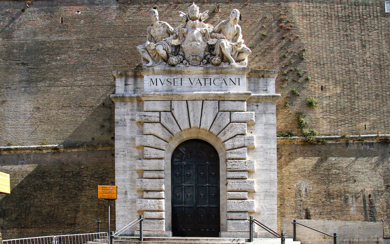 Entrance to the Vatican Museums with sculptures above the door in Rome.
