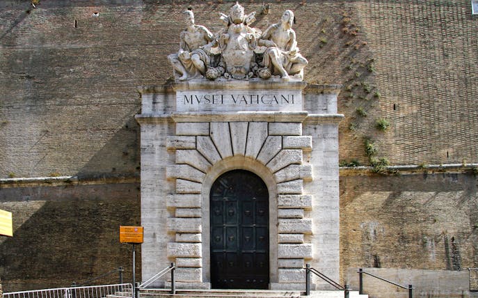 Entrance to the Vatican Museums with sculptures above the door in Rome.